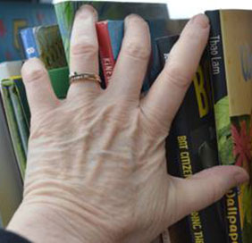 photo of a hand reaching for book on a shelf