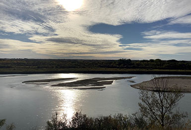 sun shining on river with sandbars
