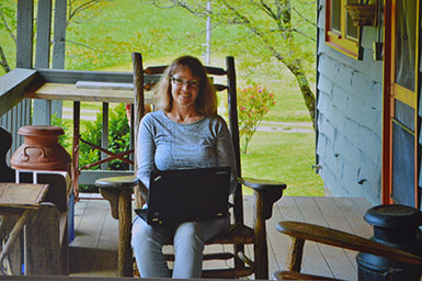 Bev sitting on a porch with a laptop on her lap
